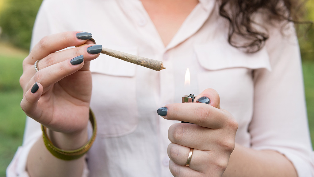 Une femme allume un joint.