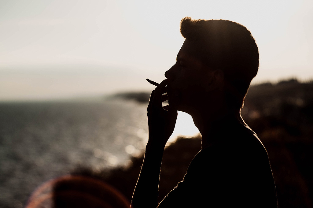 Un homme fume du cannabis dehors au coucher du soleil.