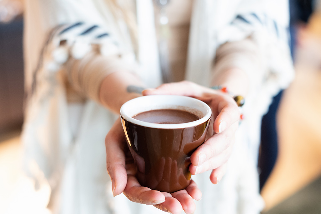 Une femme offre une tasse de chocolat chaud.